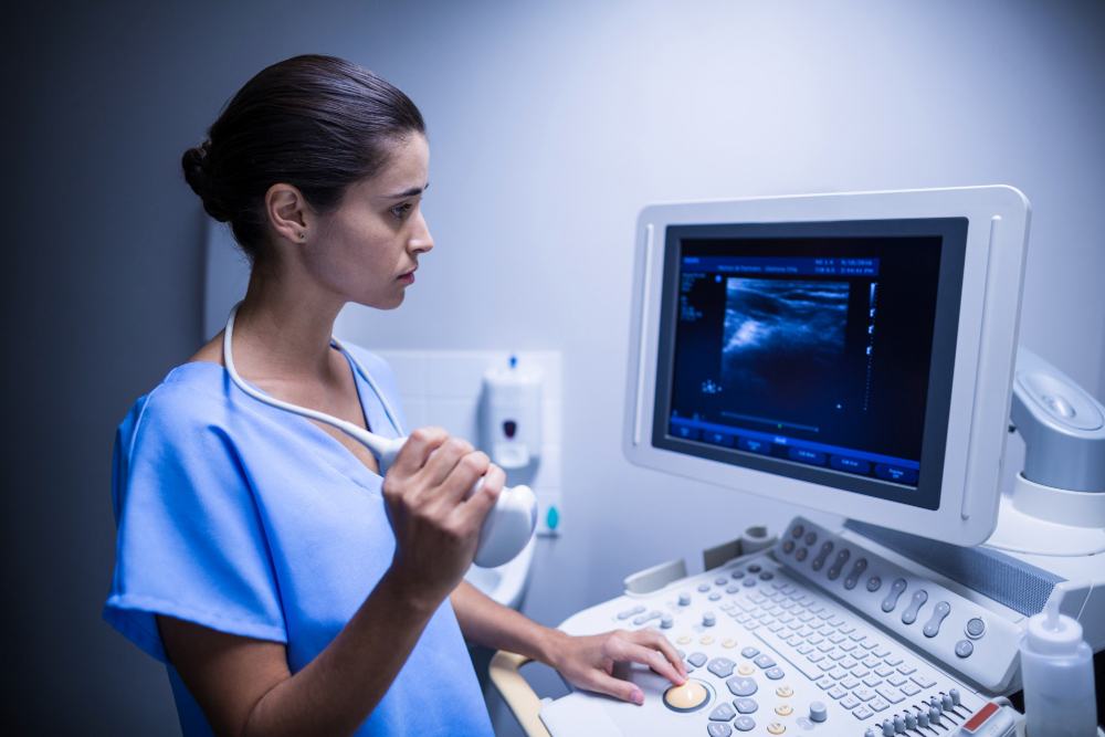 Cardiac sonographer holding an ultrasound probe beside the echo machine
